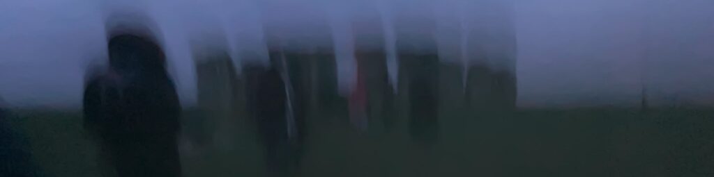 A blurred, twilight photo of the standing stones of Stonehenge on a cold, misty Winter Solstice evening